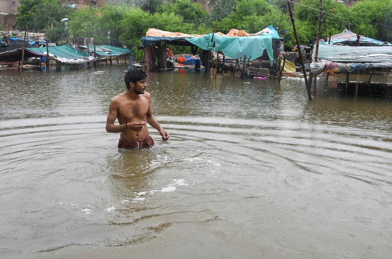 24 اگست کو پاکستان کے حیدرآباد میں مون سون کے موسم کے دوران بارش کے بعد پس منظر میں ڈوبے ہوئے خیموں کے ساتھ ایک شخص سیلاب کے پانی کے درمیان چل رہا ہے۔ — رائٹرز