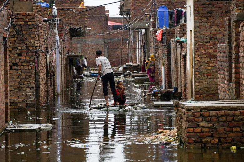 24 اگست کو پاکستان کے حیدرآباد میں مون سون کے موسم میں بارش کے بعد ایک مرد اور لڑکی سیلاب زدہ گلی کو عبور کرتے ہوئے عارضی بیڑا استعمال کر رہے ہیں۔ — رائٹرز