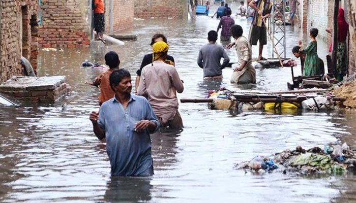 Rain effected people by flash flood after torrential rain are using a floating wooden raft made by ladder at home for transportation in flooded streets at Jinnah colony Latifabad as new heavy spell of monsoon rain hits the city. — APP