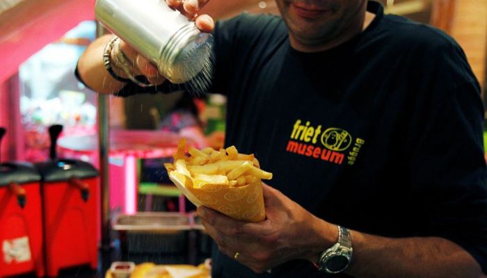 A cook sprinkles salt on fries at a cafe in the Frietmuseum in Bruges September 27, 2011. — Reuters