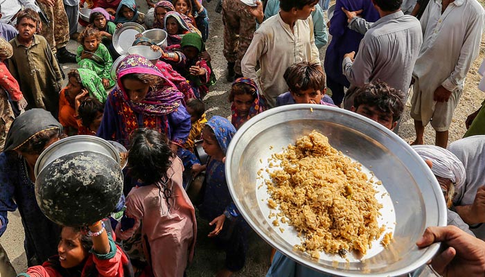 Pakistan army personnel distribute food to flood affected people near a makeshift camp following heavy monsoon rainfall in Rajanpur district of Punjab province on August 27, 2022. β AFP