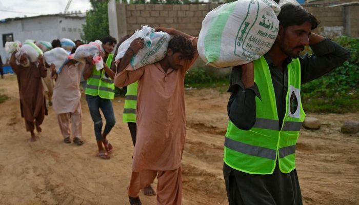 Volunteers carry relief goods bags to load on a truck in Karachi — AFP