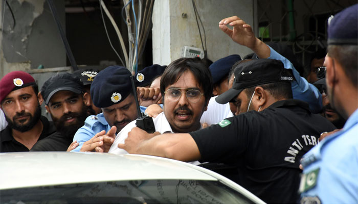 Police officers escort the leader of PTI Dr Shahbaz Gill after a hearing at district court, in Federal Capital. — Online