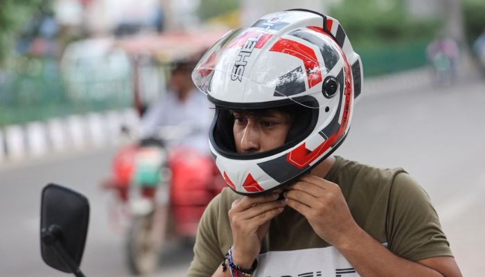 An employee of Shellios Technolabs, that manufactures motorcycle helmet claimed to be fitted with filters and a fan at the back of the helmet, puts on the helmet, near their assembling factory unit in an industrial area, in New Delhi, India, August 23, 2022.— Reuters