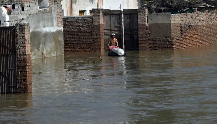 A resident wades through a flood hit area following heavy monsoon rains in Charsadda district of Khyber Pakhtunkhwa on August 29, 2022. — AFP