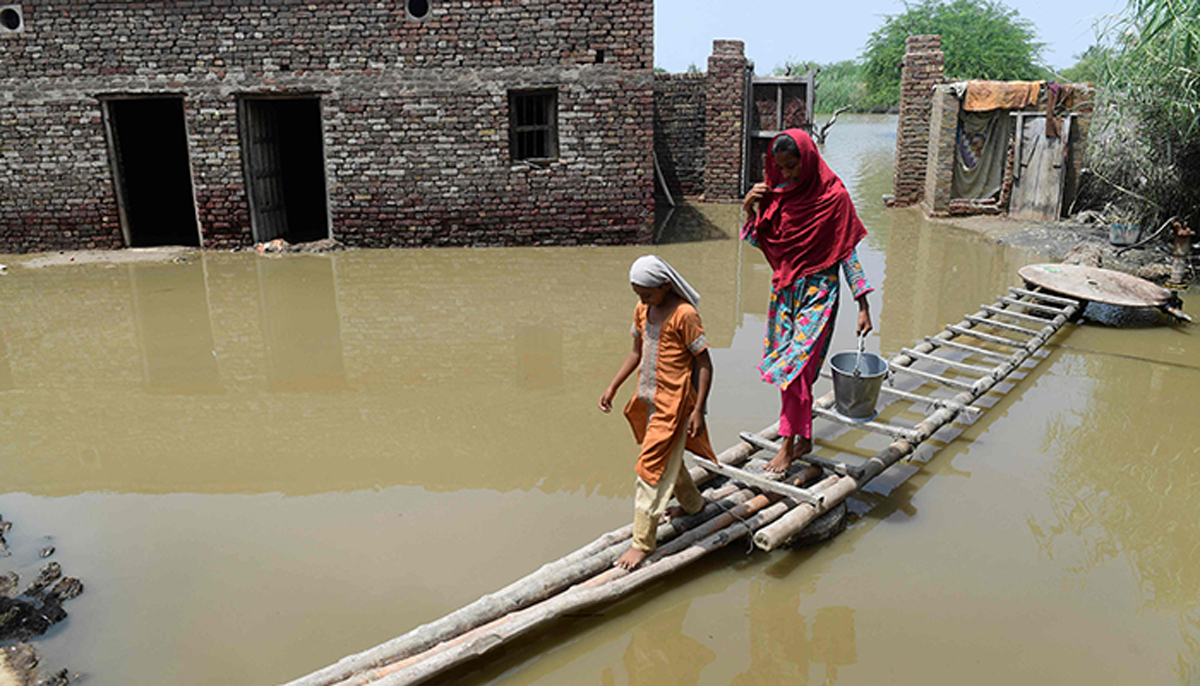 Flood-affected people walk on a temporary bamboo path near their flooded house in Shikarpur of Sindh province on August 29, 2022. — AFP