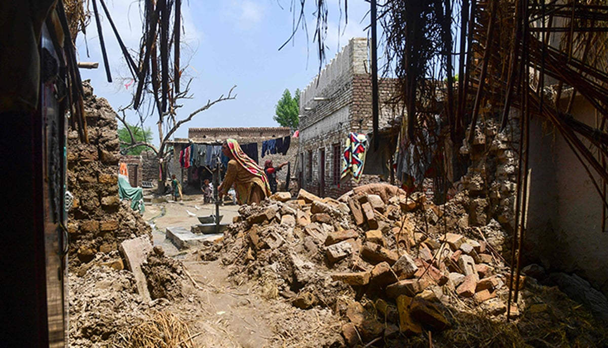 29 اگست 2022 کو صوبہ سندھ کے شکار پور میں مون سون کی شدید بارشوں کے بعد سیلاب سے متاثرہ ایک خاتون سیلاب زدہ علاقے میں اپنے تباہ شدہ گھر پر ہینڈ پمپ سے پانی بھر رہی ہے۔ — اے ایف پی