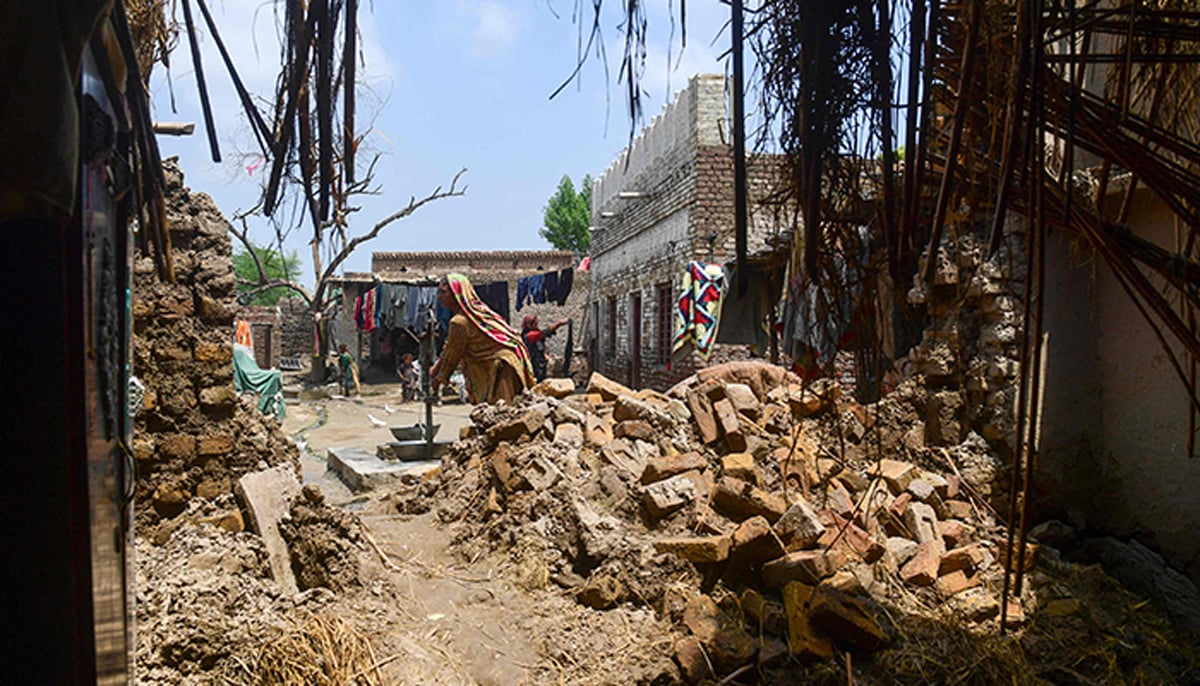 A flood-affected woman fills water from a handpump at her damaged house in a flood-hit area following heavy monsoon rains in Shikarpur of Sindh province on August 29, 2022. — AFP