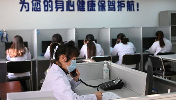 A hotline operator for a free counselling service answers a phone while wearing a face mask, as the country is hit by an outbreak of the novel coronavirus, in Shenyang, Liaoning province, China February 12, 2020. Photo: Reuters