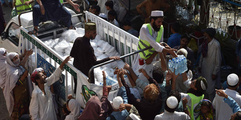 Displaced flood affected people receive food packets at a makeshift camp in Nowshera of Khyber Pakhtunkhwa province on August 29, 2022. — AFP