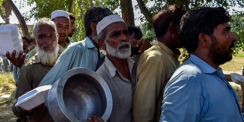 Displaced flood affected people receive food packets at a makeshift camp in Nowshera of Khyber Pakhtunkhwa province on August 29, 2022. — AFP