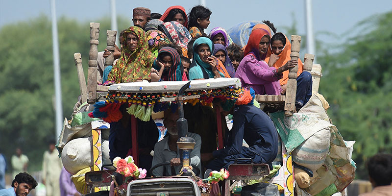 سکھر، صوبہ سندھ میں 29 اگست 2022 کو ہونے والی مون سون کی شدید بارشوں کے بعد سیلاب زدہ گھروں سے نقل مکانی کرنے کے بعد بے گھر افراد ایک عارضی کیمپ میں اپنا سامان لے کر ٹریکٹر پر پہنچ رہے ہیں۔ — اے ایف پی