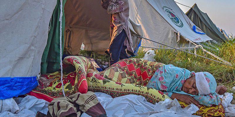 29 اگست 2022 کو خیبر پختونخواہ کے ضلع چارسدہ میں مون سون کی شدید بارشوں کے بعد سیلاب زدہ گھر سے فرار ہونے کے بعد ایک بے گھر خاتون عارضی کیمپ میں خیمے میں سو رہی ہے۔ — اے ایف پی