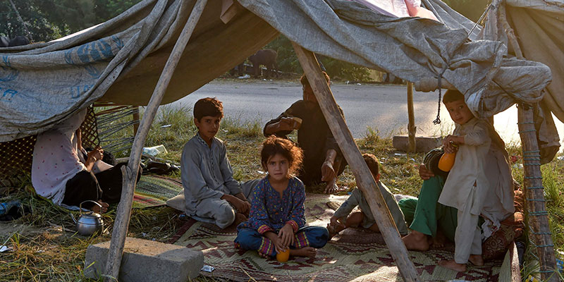 29 اگست 2022 کو خیبر پختونخوا کے ضلع چارسدہ میں مون سون کی شدید بارشوں کے بعد سیلاب زدہ گھروں سے نقل مکانی کے بعد بے گھر افراد عارضی کیمپ میں اپنے خیموں میں ناشتے کی تیاری کر رہے ہیں۔ — اے ایف پی