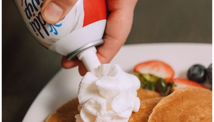 A Person Putting Whipped Cream on the Pancakes.— Pexel