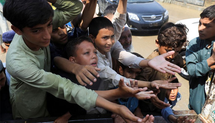 Boys, victims of the flood, reach out for food from a relief worker, following rains and floods during the monsoon season in Nowshera, Pakistan August 30, 2022. — Reuters