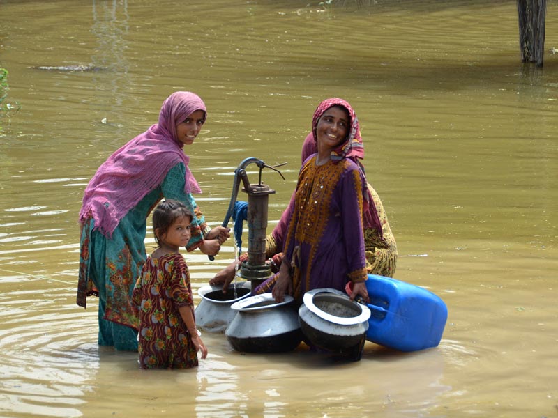 Flood-affected women fill drinking water from a handpump amid a flooded street following heavy monsoon rains in the Jaffarabad district of Balochistan province on August 29, 2022. — AFP/ Fida Hussain