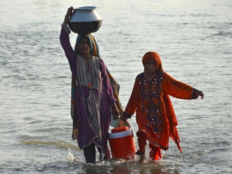 Flood-affected women carry drinking water in containers after fleeing from their flood-hit homes following heavy monsoon rains in the Sohbatpur area in Jaffarabad district of Balochistan province on August 28, 2022. — AFP/ Fida Hussain