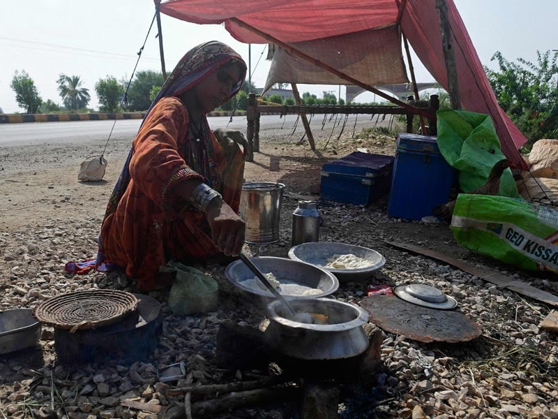 A displaced flood-affected woman prepares food on dry ground for her family after fleeing from a flood-hit home at Shikarpur in Sindh province on August 30, 2022. — AFP/ Asif Hassan