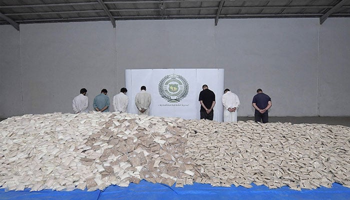 An handout picture released by the Saudi Interior Ministry on August 31, 2022, shows handcuffed suspects and bags of amphetamine pills on display at a warehouse in a undisclosed location. — AFP