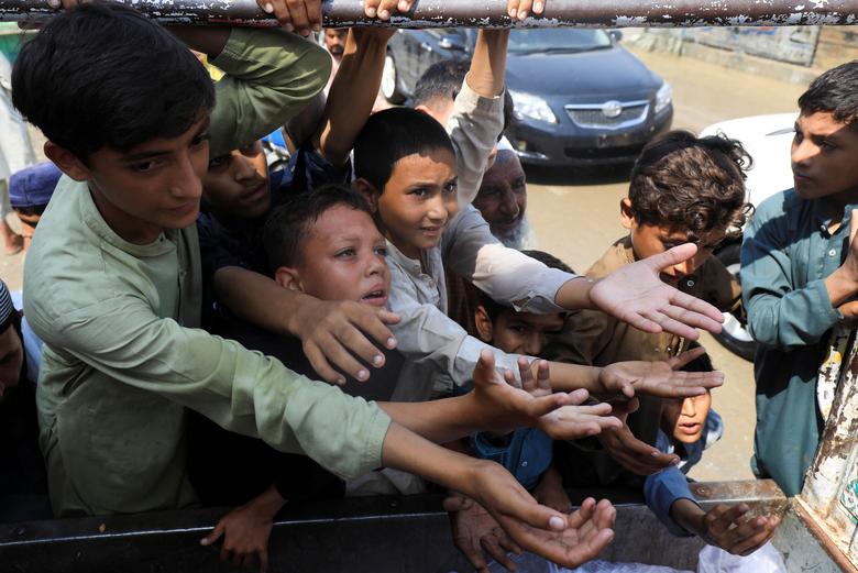 Boys, victims of the flood, reach out for food from a relief worker, following rains and floods during the monsoon season in Nowshera, Pakistan, August 30.