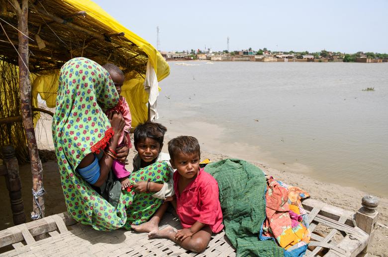 جامشورو، پاکستان میں 26 اگست 2022 کو مون سون کے موسم کے دوران بارشوں اور سیلاب کے بعد ایک عورت اور بچے اونچی زمین پر پناہ لینے کے بعد اپنے خیمے کے باہر بیٹھے ہیں۔