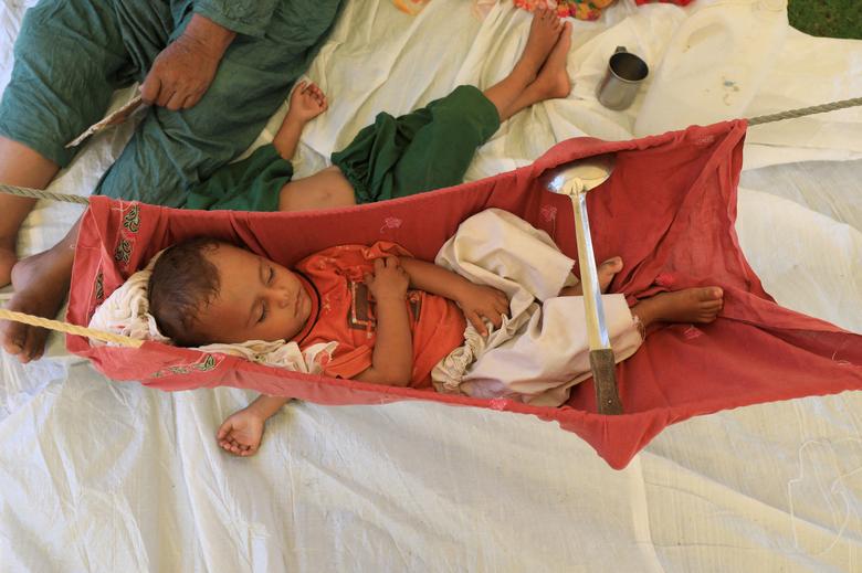28 اگست 2022 کو چارسدہ، پاکستان میں مون سون کے موسم کے دوران بارشوں اور سیلاب کے بعد ایک بچہ جھولا میں سو رہا ہے جب خاندان ایک خیمے میں پناہ لے رہا ہے۔