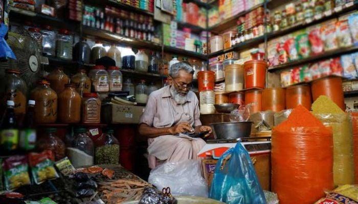 A shopkeeper can be seen calculating at his grocery store. — Reuters