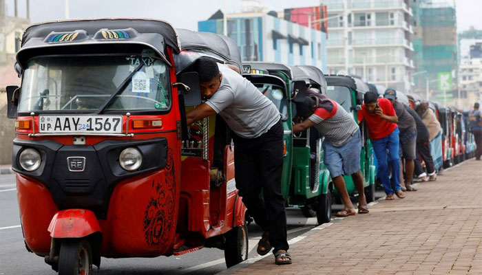 Drivers push auto rickshaws in a line to buy petrol from a fuel station, amid Sri Lankas economic crisis, in Colombo, July 29, 2022. — Reuters