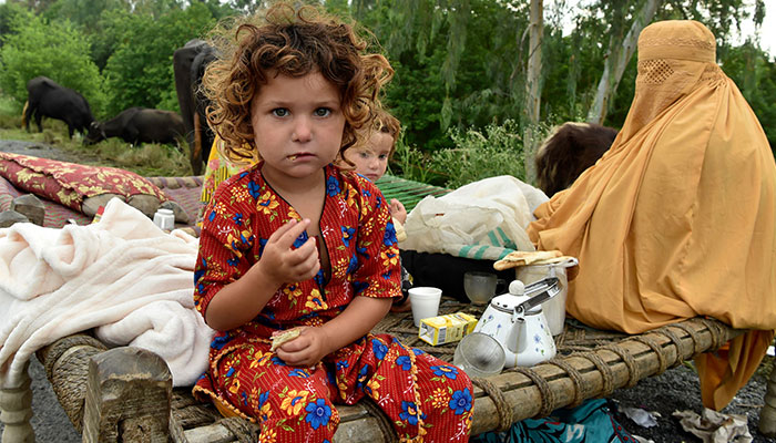 Displaced people take refuge along a highway after fleeing from their flood hit homes following heavy monsoon rains in Charsadda district in Khyber Pakhtunkhwa on August 27, 2022. — AFP