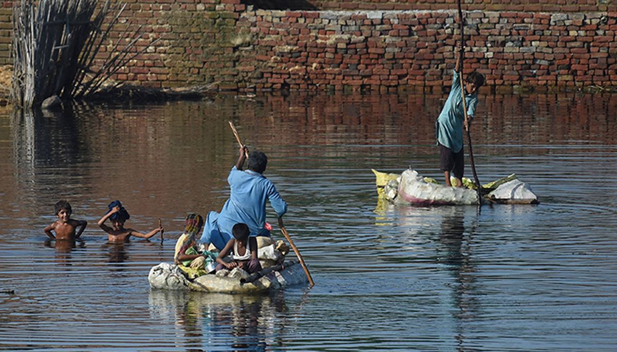 People use rafts to cross a flooded area after monsoon rains on the outskirts of Sukkur, Sindh province, on September 1, 2022. — AFP