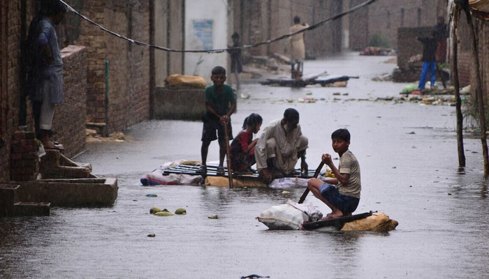 Children and a man seen sitting on makeshift boats to move in streets inundated with flood water in Hyderabad. — AFP/File
