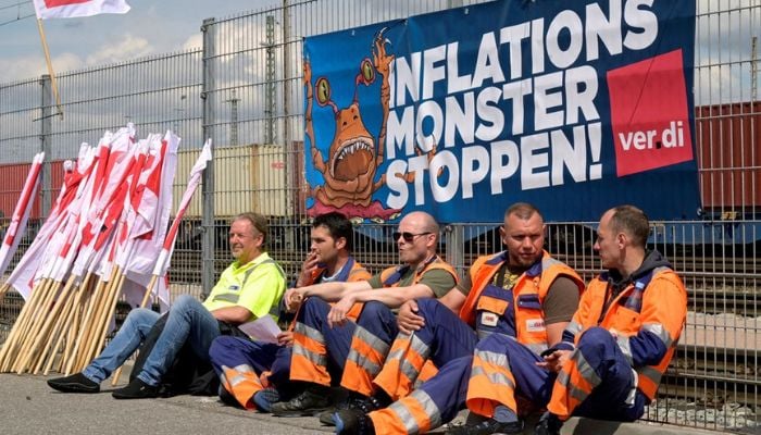Workers sit in front of a banner reading Stop the Inflation Monster at the Burchardkai Container Terminal as they go on strike for higher wages in the harbour in Hamburg, Germany, June 9, 2022. — Reuters