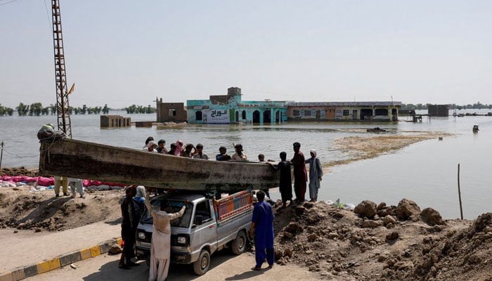 People launch a wooden boat into rising flood waters on the Indus highway, following rains and floods during the monsoon season in Mehar, Pakistan, August 31, 2022. — Reuters