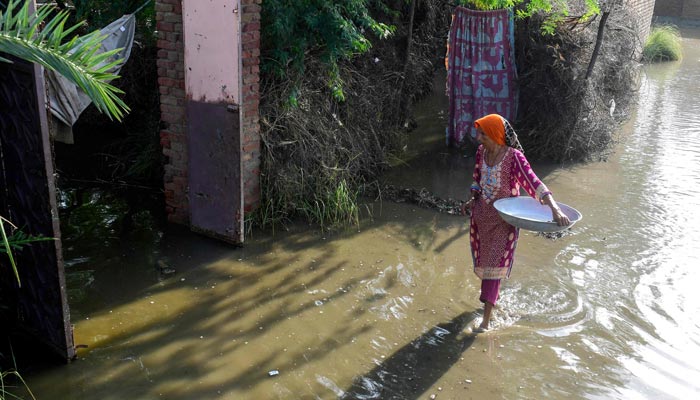 A flood affected woman wades across a street in Sukkur, Sindh province on September 2, 2022.