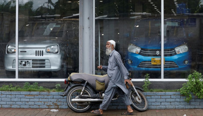 A man walks past a Suzuki outlet, displaying cars in Karachi, Pakistan, July 27, 2022. — Reuters