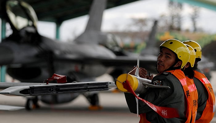 Air force crews lift an AIM-9 Sidewinder air-to-air missiles to be loaded onto Northrop F-5 fighter during a military drill at Zhi-Hang Air Base in Taitung, Taiwan January 30, 2018. — Reuters