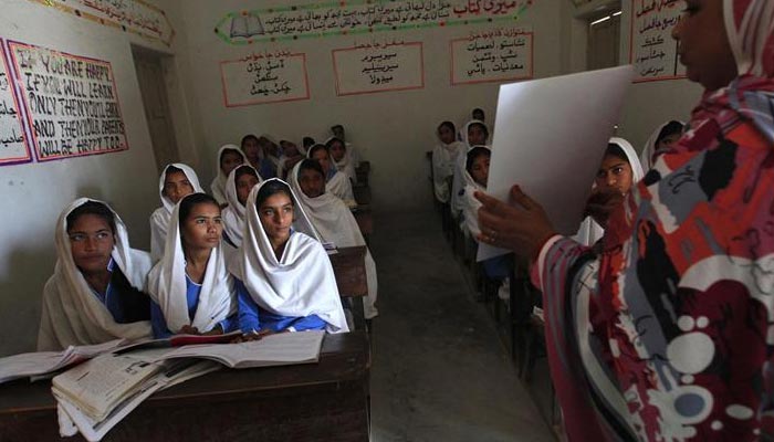 A teacher displays a flash card to students during a class at a school in Pir Mashaikh village in Johi, a town located between Balochistan and Sindh, Pakistan, February 12, 2014. REUTERS/Akhtar Soomro/Files