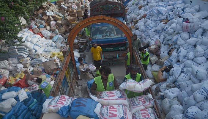 Volunteers of the Charity Al-Khidmat Foundation load relief bags onto trucks for flood-affected people in Karachi on September 3, 2022. — AFP