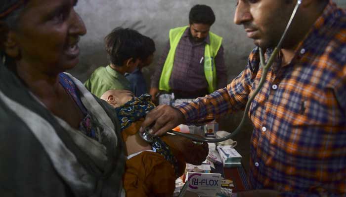 A doctor is checking a flood-hit minor girl at a medical camp. Photo: AFP