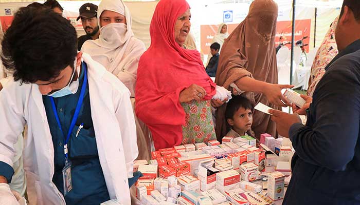 Women receive medical assistance while taking refuge in a relief camp in Charsadda, KP. Photo: Reuters