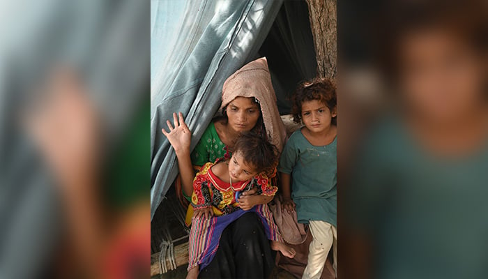 3 ستمبر 2022 کو صوبہ پنجاب کے ضلع راجن پور کے فاضل پور میں ریلوے ٹریک کے ساتھ ایک عارضی کیمپ میں سیلاب سے متاثرہ حاملہ خاتون سائرہ بی بی اپنے بچوں کے ساتھ اپنے خیمے پر بیٹھی ہے۔