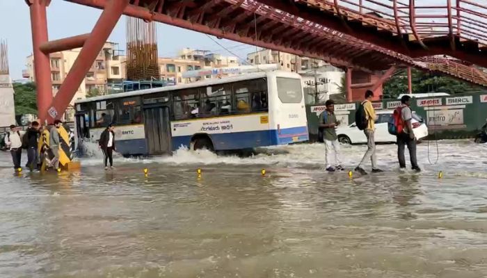 People walk next to a bus driving along a waterlogged road in Bengaluru, Karnataka state, India in this screen grab taken from a social media video September 5, 2022. — Reuters