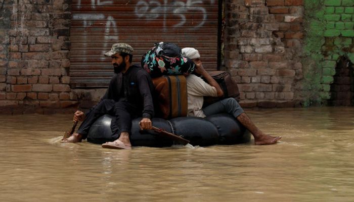 A volunteer paddles an inflatable tube as he evacuates a flood victim with his belongings, following rains and floods during the monsoon season in Charsadda.— Reuters