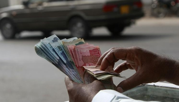 A money changer counts Pakistani Rupee (PKR) notes in Karachi September 23, 2009. — Reuters
