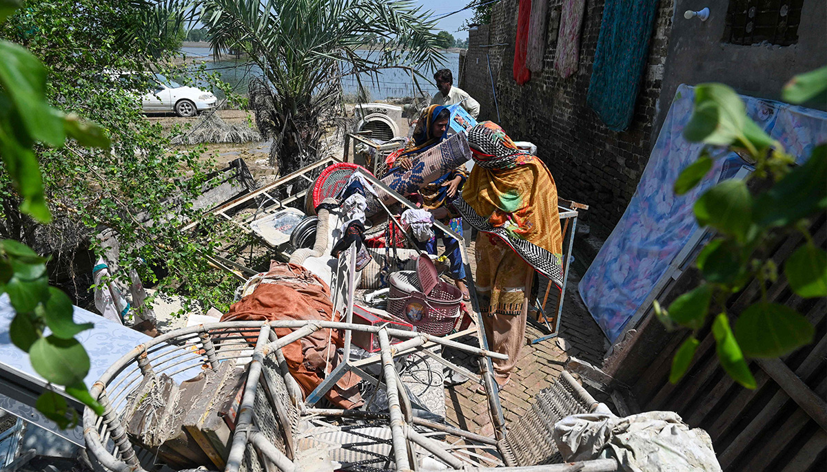 Mureed Hussain helps other family members to dry the dowry belongings of his daughter Nousheen, which were damaged by flood waters at his house in Fazilpur, Rajanpur district of Punjab province on September 3. — AFP
