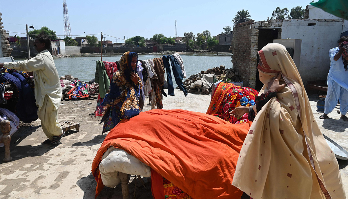 Mureed Hussain helps other family members to dry the dowry belongings of his daughter Nousheen, which was damaged by flood waters at his house in Fazilpur, Rajanpur district of Punjab province on September 3, 2022. — AFP