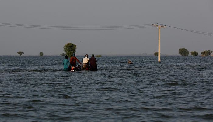 Men walk with their motorcycles amid flood water, following rains and floods during the monsoon season in Bajara village, at the banks of Manchar lake, in Sehwan, Pakistan September 6, 2022. — Reuters