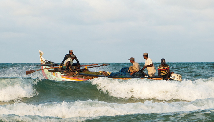 مقامی ماہی گیروں کا ایک گروپ 17 اگست 2022 کو سری لنکا کے منار کے ساحل پر اپنی کشتی میں سمندر کی طرف روانہ ہو رہا ہے۔ — رائٹرز