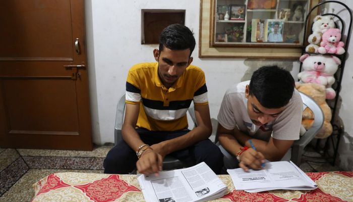 Vijay Chauhan, 18, and Vishal, 18, who both take English language classes at Western Overseas institute, go through their notes at Vijays house in the village of Adhoya in Ambala district, India, August 15, 2022.— Reuters